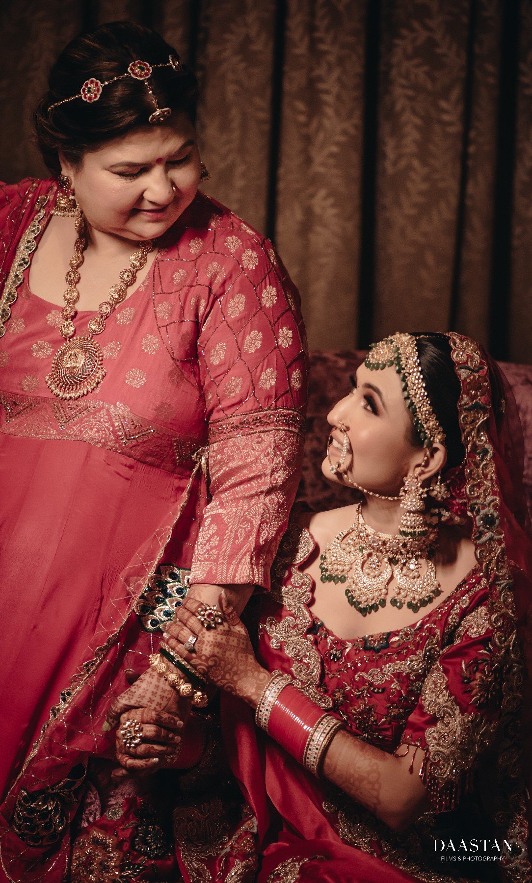 Bride being dressed by family during getting-ready ceremony, candid Indian wedding production photography