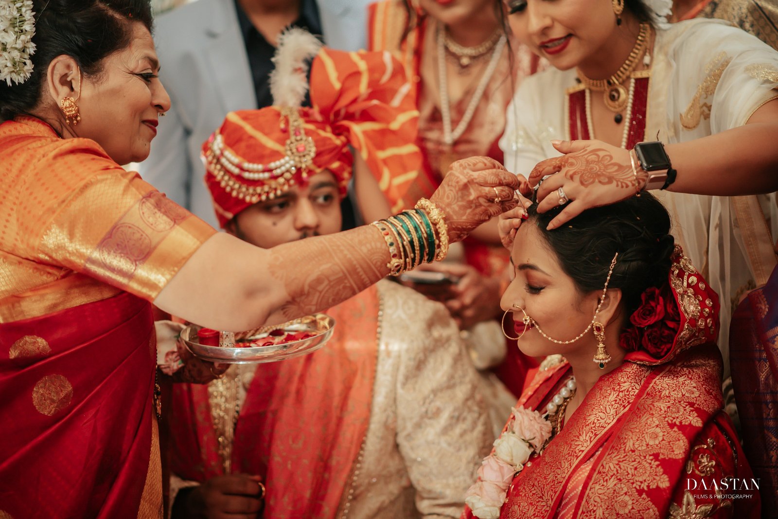Family adorning bride with jewellery during wedding ritual, candid Indian wedding photography