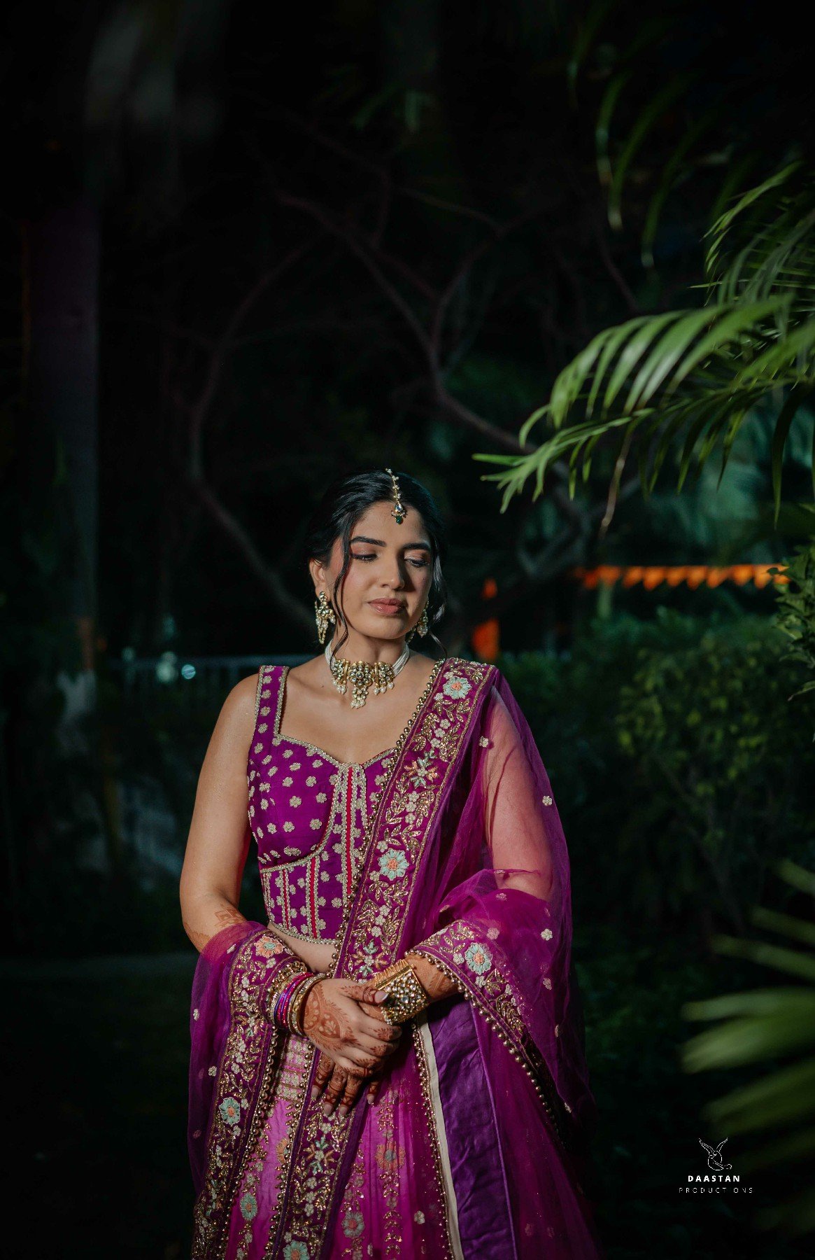 Bride in pastel pink lehenga in botanical setting, editorial-style wedding photography India