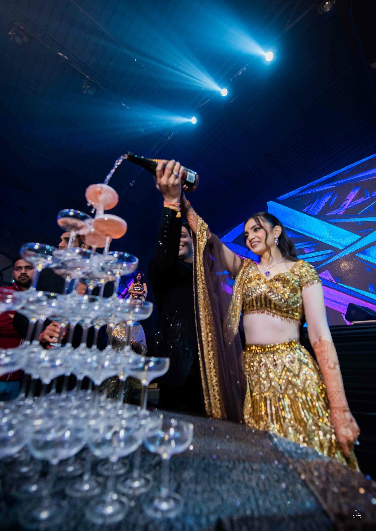 Bride performing on stage during sangeet night with vibrant lighting, professional wedding coverage India