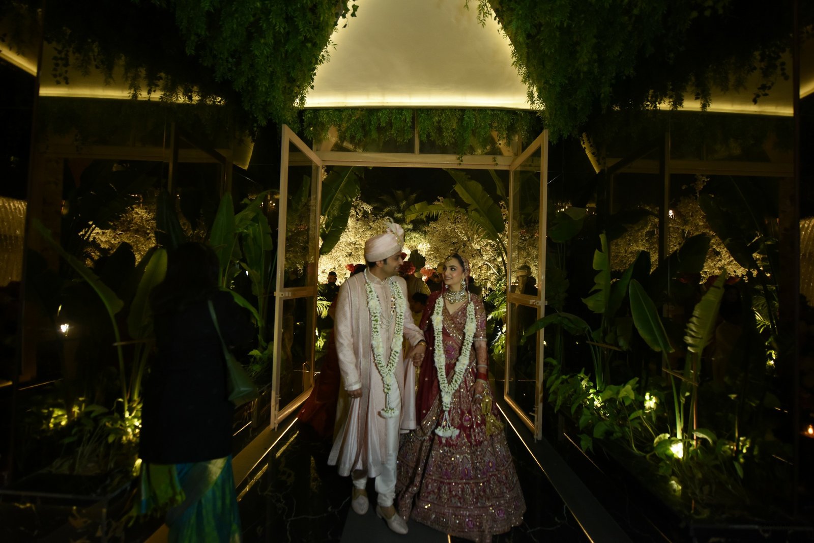 Couple making grand entry at wedding reception through lush floral decor, luxury wedding photography India