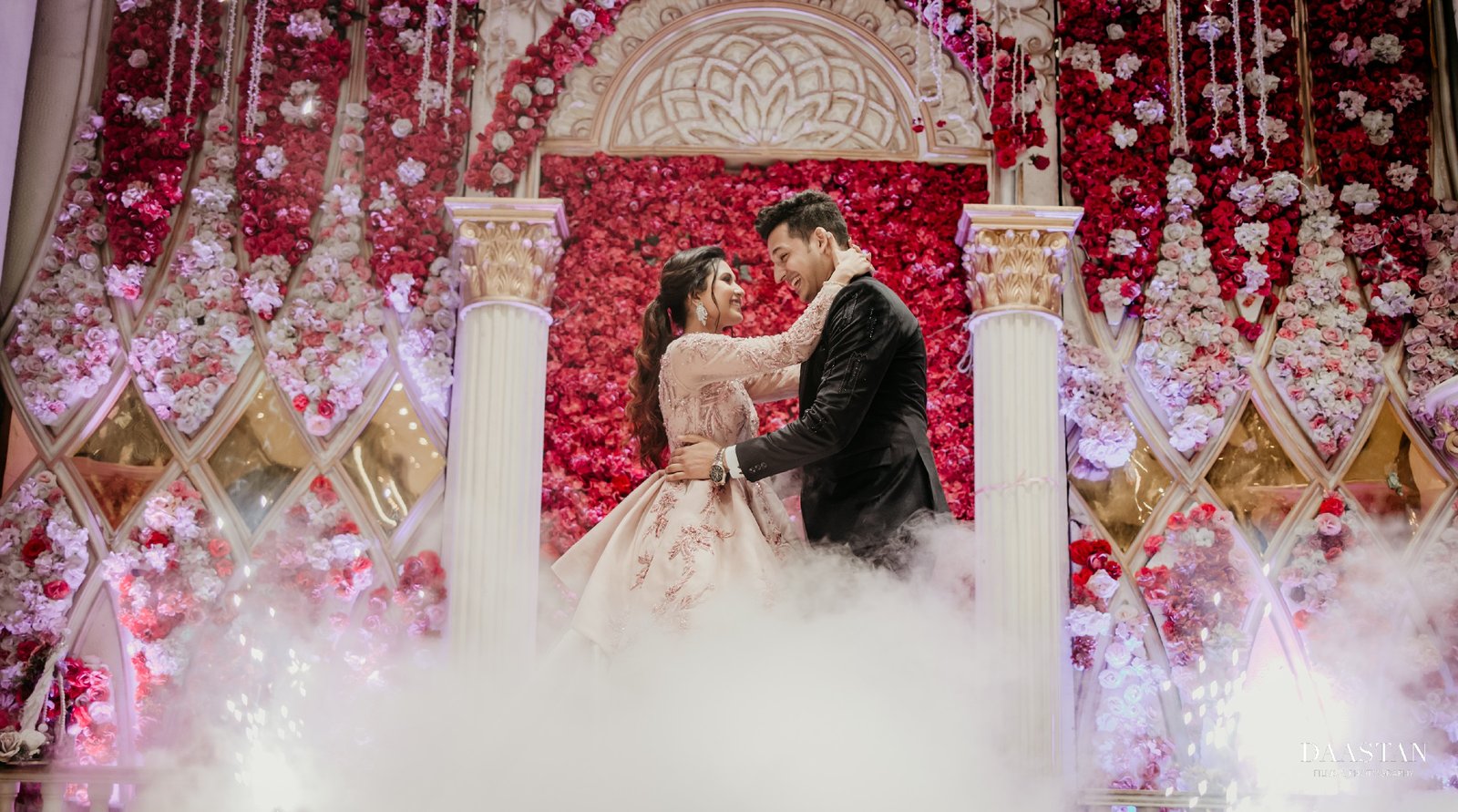 Romantic couple portrait in front of rose wall at Indian wedding reception, luxury photography