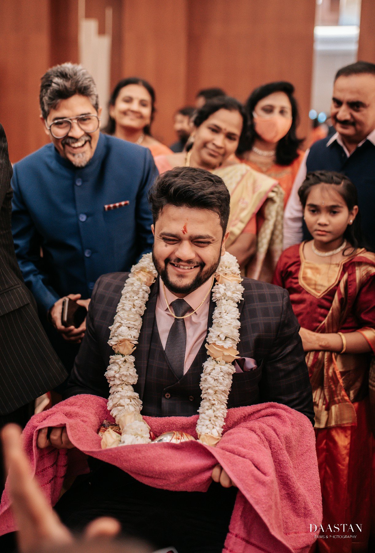 Groom in sherwani with flower garland during jaimala ceremony, candid Indian wedding photography