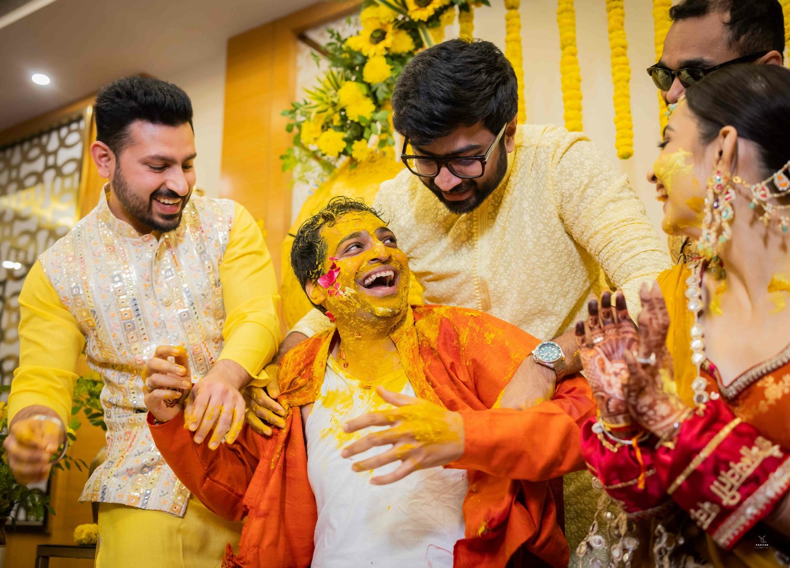 Family applying haldi to bride and groom during traditional Indian wedding haldi ceremony