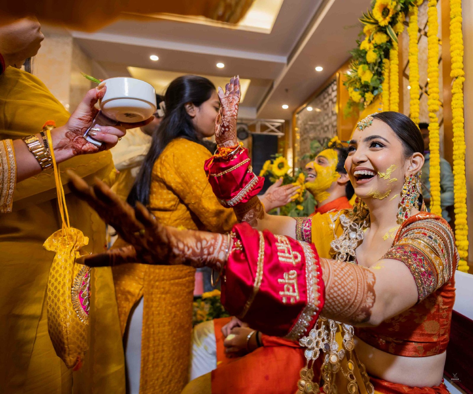 Fun water splash moment during haldi ceremony, candid Indian pre-wedding ritual photography