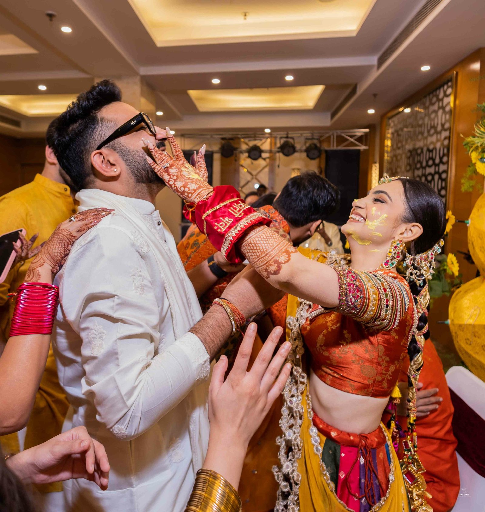 Playful haldi moment with bride and groom laughing during turmeric ritual, candid Indian wedding photography
