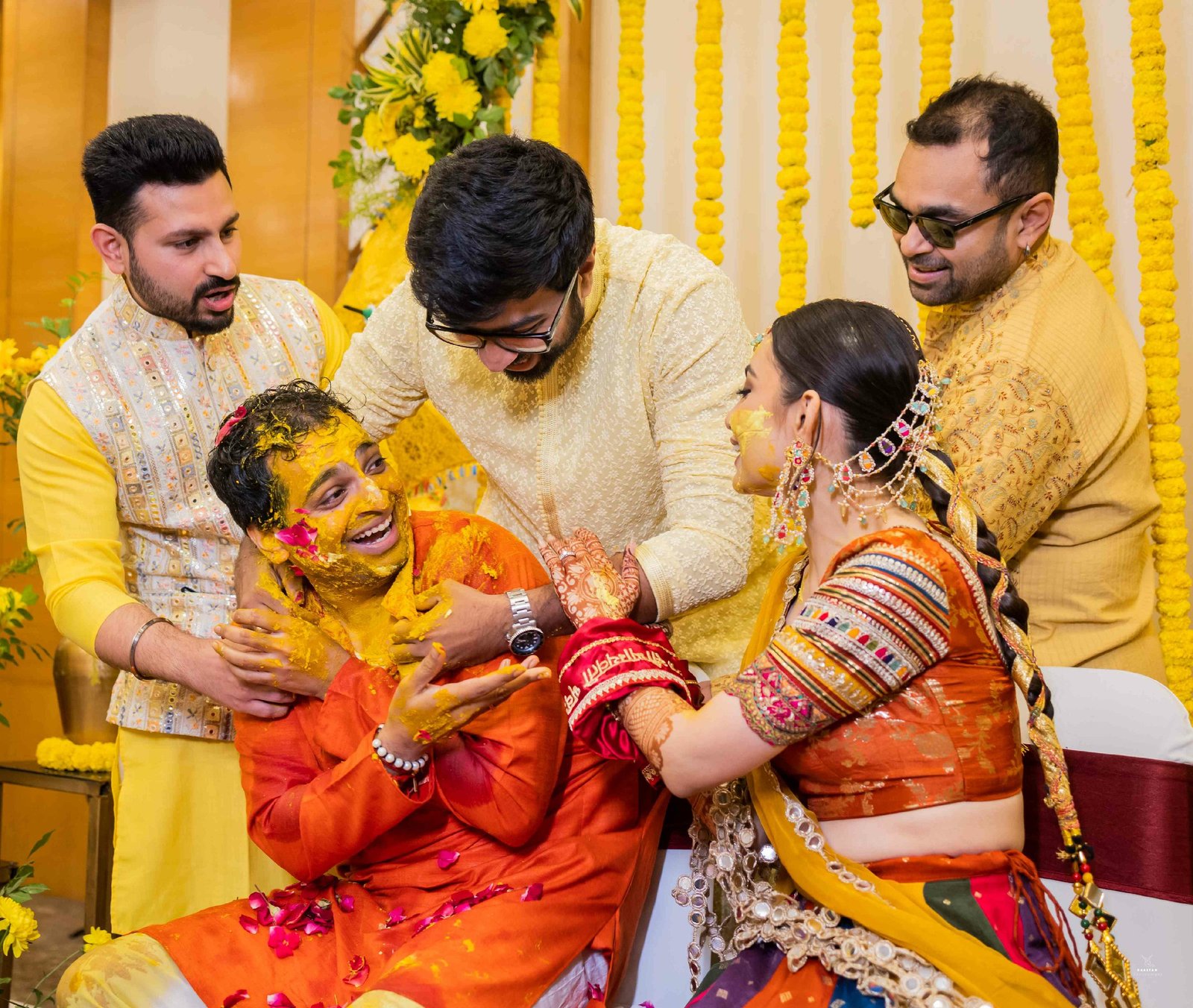 Family applying turmeric paste to bride in traditional Indian haldi ceremony, candid wedding photography