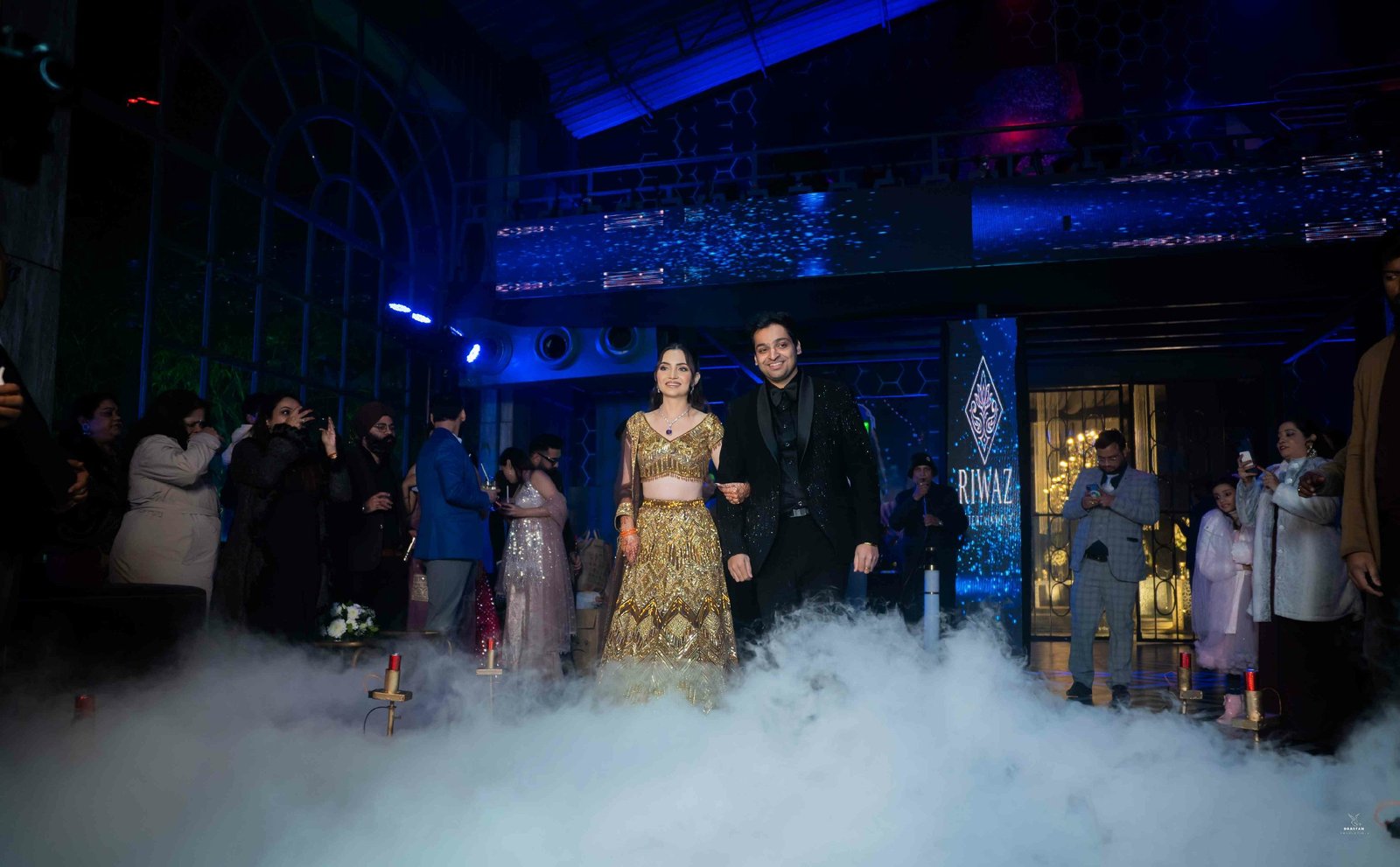 Dramatic fog-filled sangeet night entry with guests, luxury Indian wedding production photography